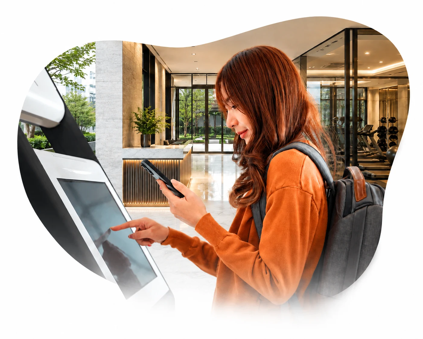 Woman holding a phone while using a touchscreen self-service kiosk