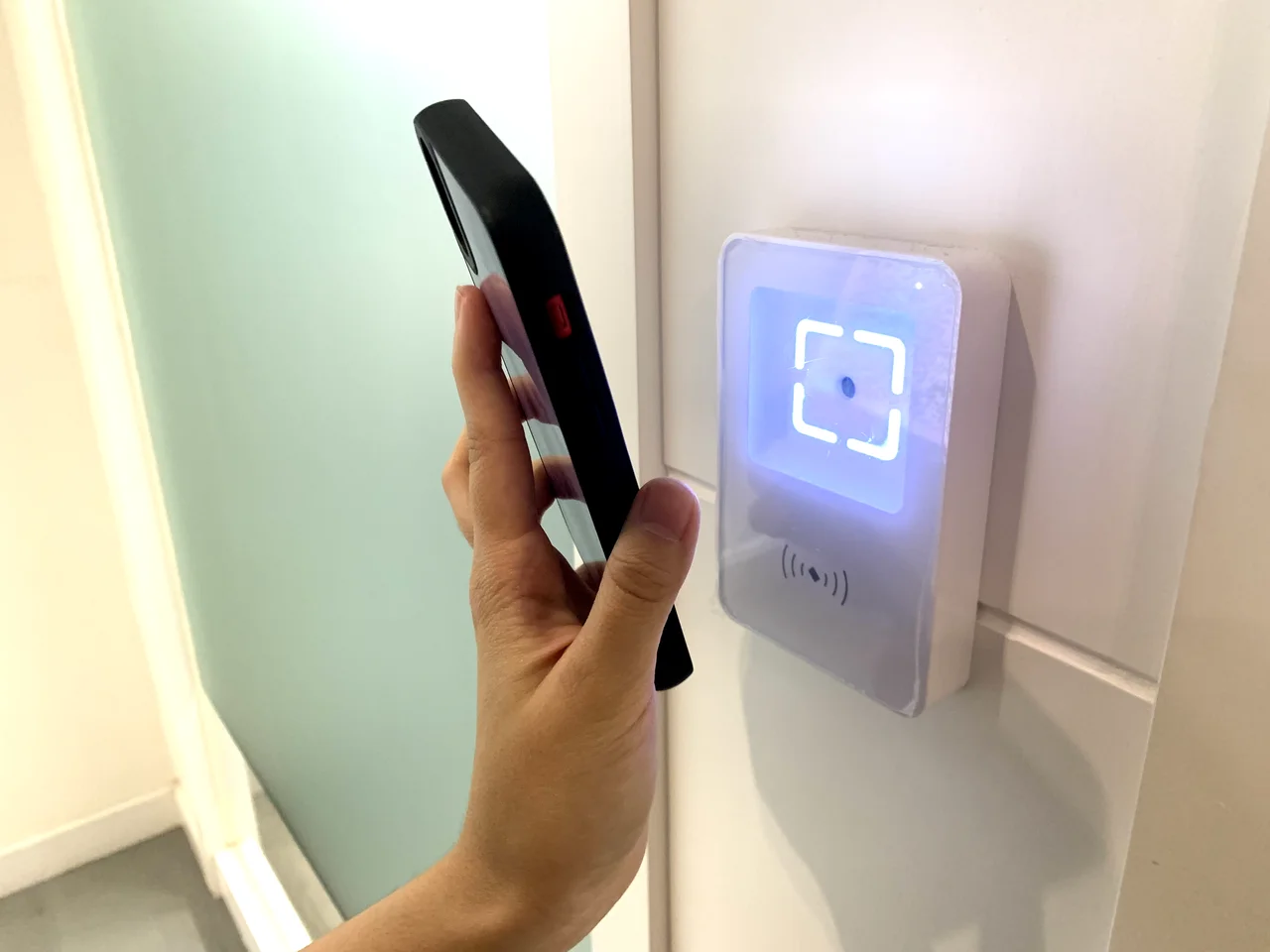 Phone held beside a wall-mounted access reader